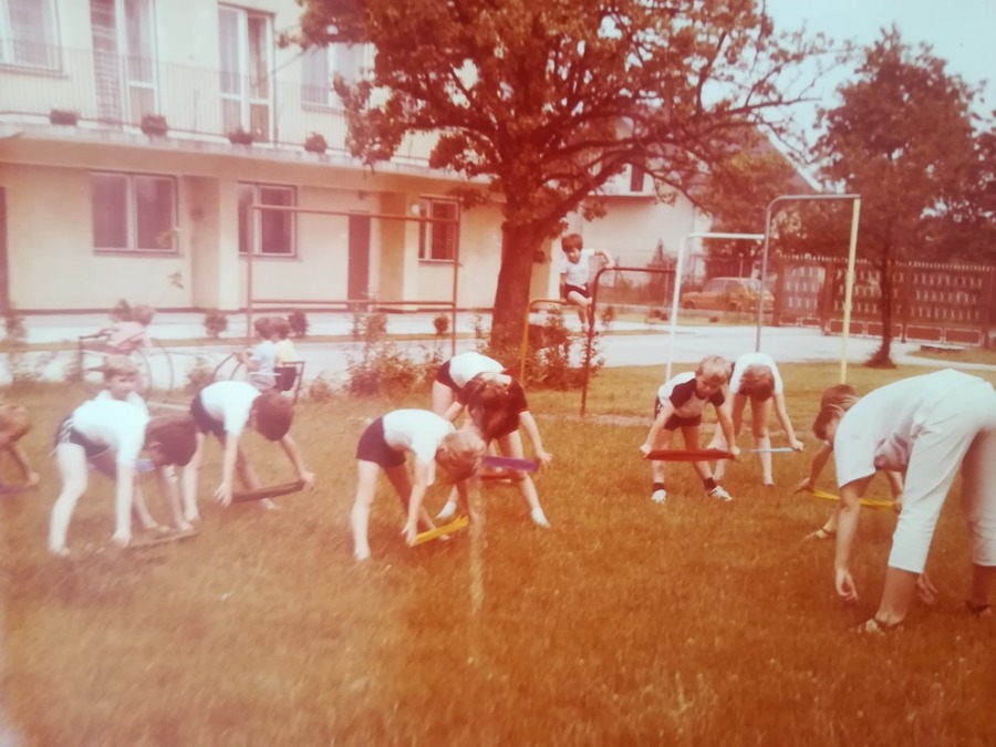 Ćwiczące dzieci na placu zabaw, w tle budynek przedszkola - stare zdjęcie